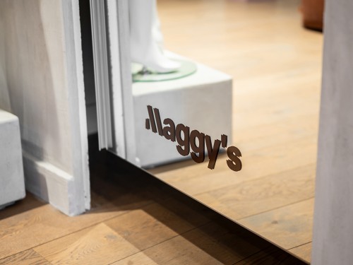 Subtiele logo-sticker onderaan een winkelspiegel in de winkel van Maggy’s