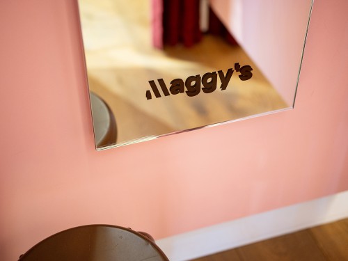 Subtiele logo-sticker onderaan een winkelspiegel in de winkel van Maggy’s