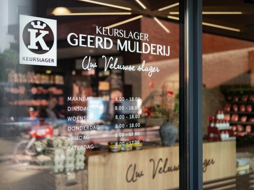 raamstyling met raamstickers van logo en openingstijden in witte glasfolie voor keurslager in voorthuizen