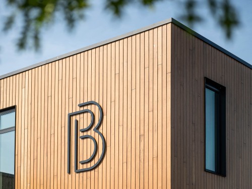 Ontwerp en productie gevellogo in zwart acrylox op houten gevel 