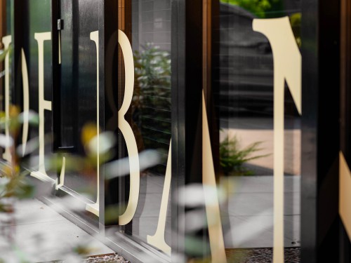 Ontwerp en productie gevellogo in beige folie op ramen en deur