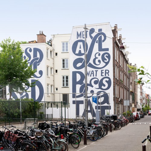 Kunstwerk Piet Parra voor school in Amsterdam, uitgevoerd door Iwaarden als muurschildering op een gevel aan het schoolplein